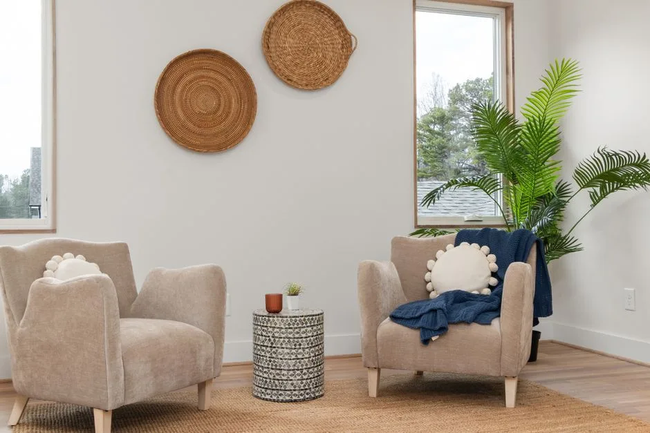 Two soft armchairs facing each other in a bright, calm room with plants
